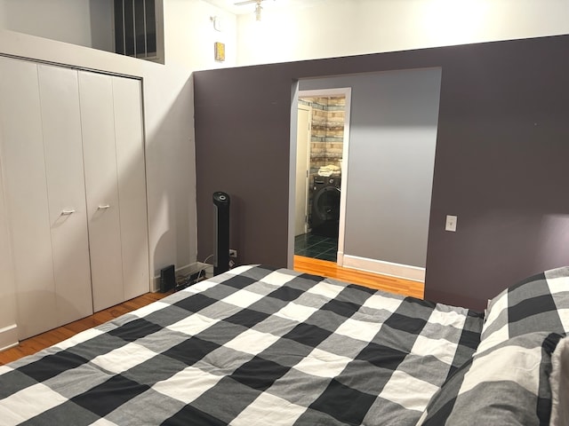 unfurnished bedroom featuring washer / dryer, hardwood / wood-style floors, ensuite bathroom, and a closet