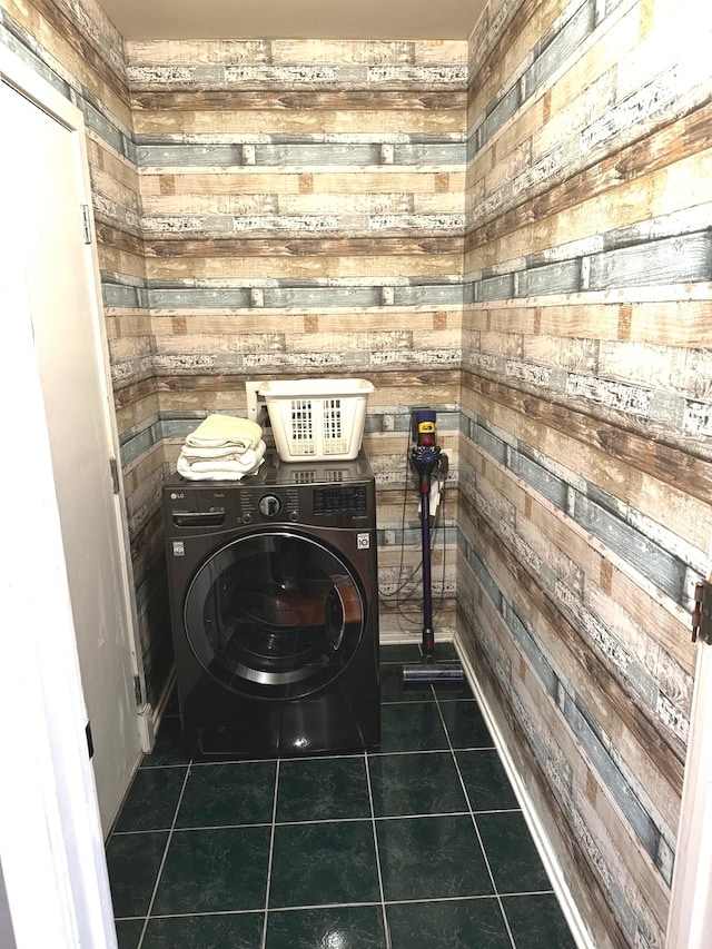 laundry area with wood walls, washer / clothes dryer, and dark tile patterned floors