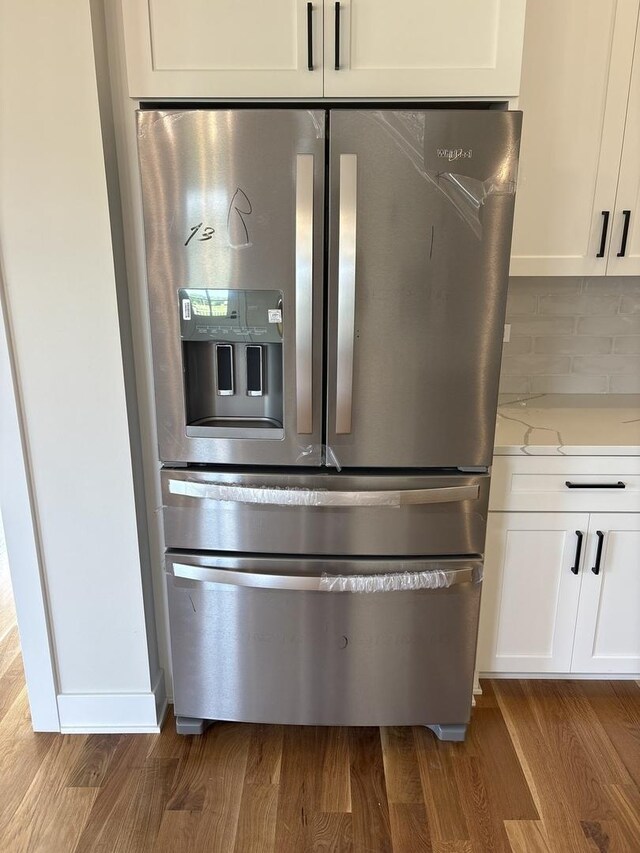9411 Tall Grass Trl, St John, IN 46373 - kitchen view of stainless steel refrigerator with ice dispenser, dark wood finished floors, backsplash, white cabinets, and light stone counters