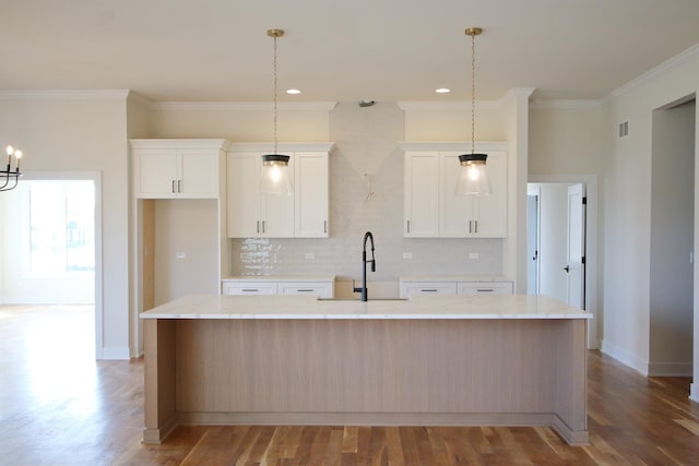 kitchen featuring tasteful backsplash, crown molding, a spacious island, light wood finished floors, and white cabinets