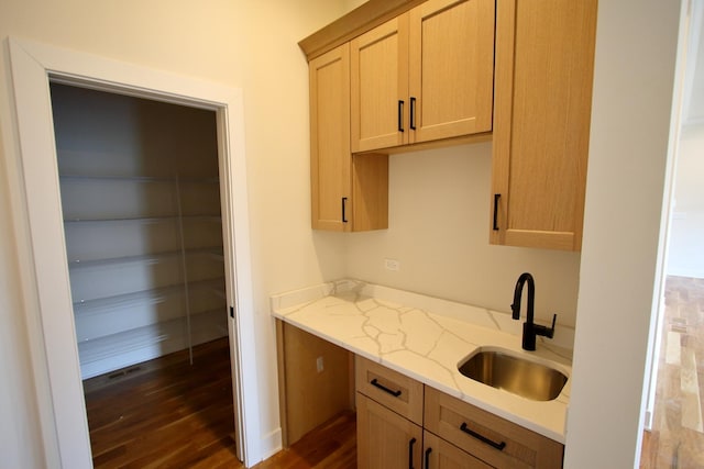 kitchen with light stone counters, visible vents, light brown cabinets, a sink, and dark wood-type flooring