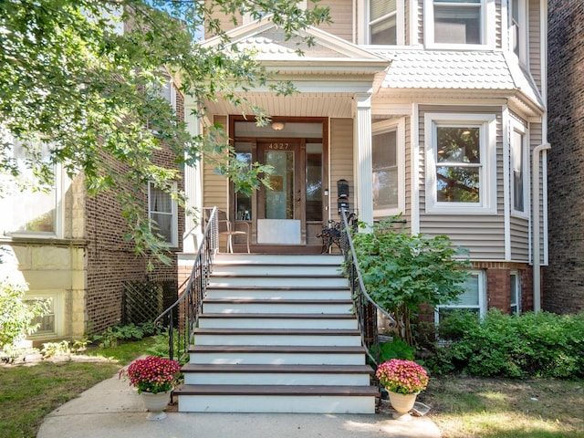 property entrance featuring a porch and brick siding