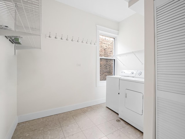 laundry room featuring laundry area, separate washer and dryer, light tile patterned flooring, and baseboards