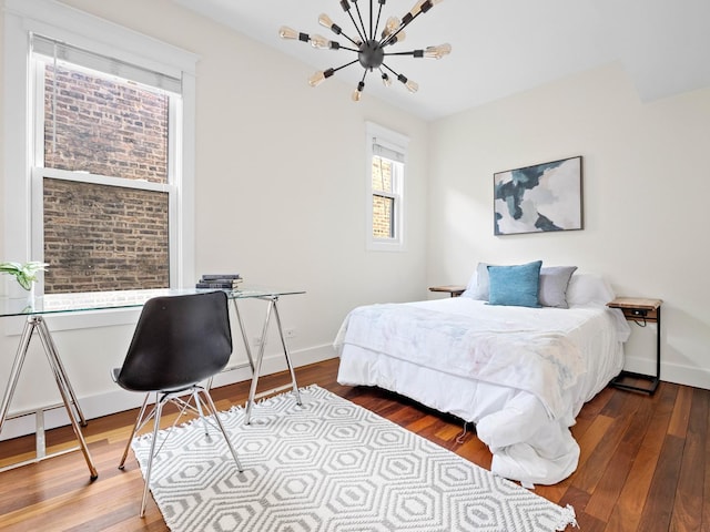 bedroom featuring an inviting chandelier, baseboards, and wood finished floors