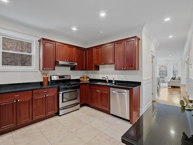 kitchen featuring crown molding, stainless steel appliances, dark countertops, a sink, and under cabinet range hood