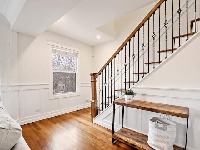 entryway with stairs, a decorative wall, wood finished floors, and recessed lighting