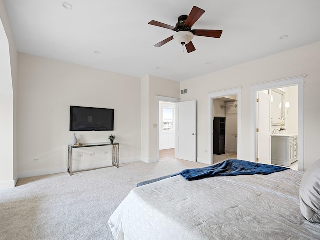 bedroom featuring light carpet, visible vents, baseboards, ceiling fan, and a walk in closet