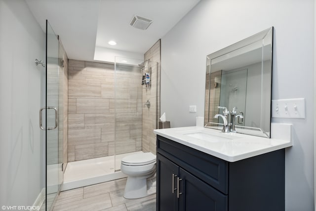 bathroom featuring a shower with door, tile flooring, oversized vanity, and toilet