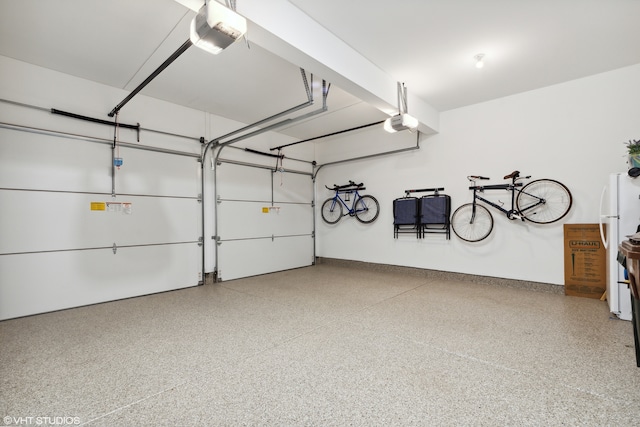 garage featuring white refrigerator and a garage door opener