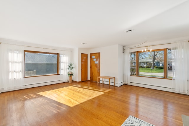 unfurnished living room with a wealth of natural light, a notable chandelier, and light wood-type flooring