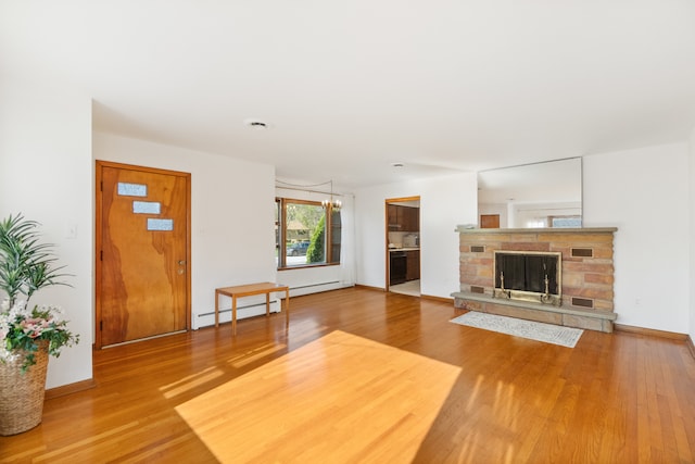 unfurnished living room with a stone fireplace, baseboard heating, and light wood-type flooring