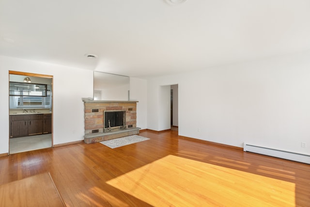 unfurnished living room with light hardwood / wood-style flooring, sink, and baseboard heating