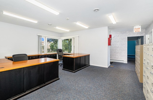 carpeted office with a baseboard heating unit