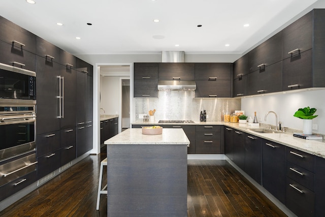 kitchen featuring sink, dark wood-type flooring, stainless steel appliances, a breakfast bar, and decorative backsplash