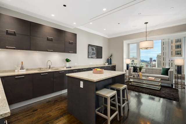 kitchen featuring a center island, dark hardwood / wood-style flooring, pendant lighting, crown molding, and a breakfast bar area