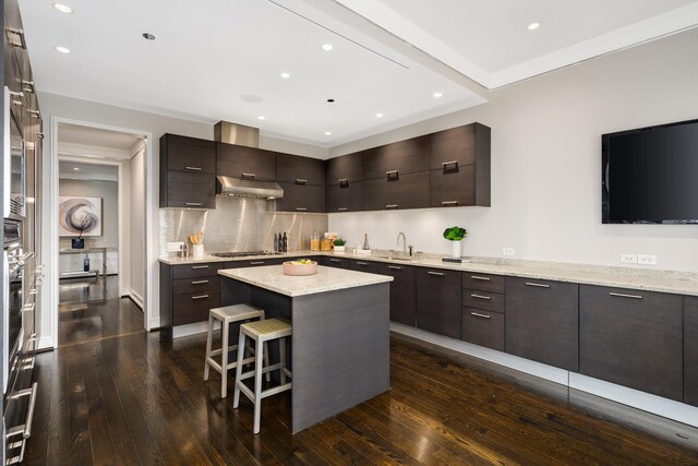 kitchen featuring a center island, dark hardwood / wood-style floors, a breakfast bar area, black gas stovetop, and dark brown cabinets