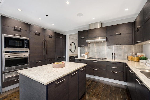 kitchen with dark brown cabinetry, tasteful backsplash, a kitchen island, stainless steel appliances, and dark hardwood / wood-style floors