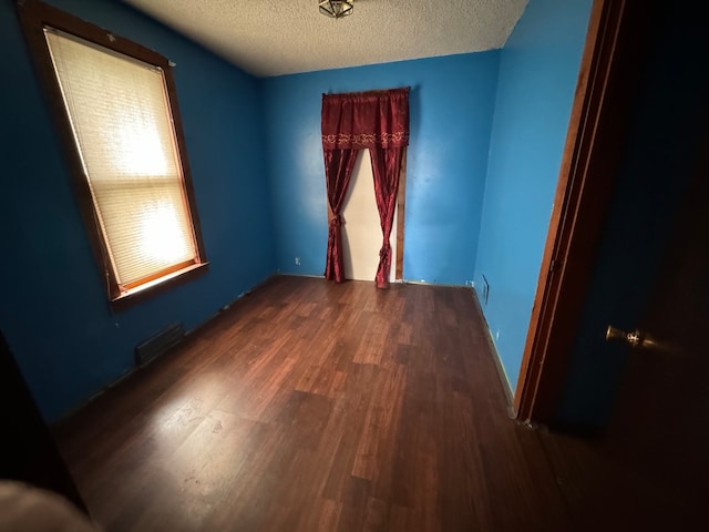 spare room with dark wood-type flooring and a textured ceiling