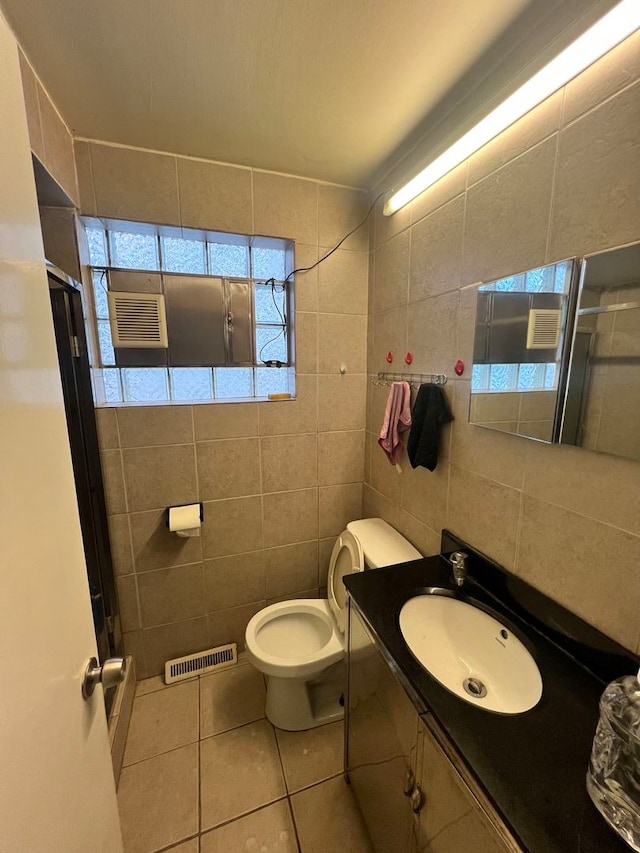 bathroom with tile walls, vanity, tile floors, and toilet