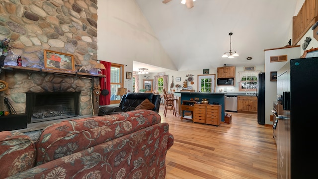 living room featuring sink, high vaulted ceiling, a fireplace, ceiling fan with notable chandelier, and light wood-type flooring