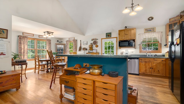 kitchen with light hardwood / wood-style flooring, pendant lighting, a chandelier, vaulted ceiling, and black appliances