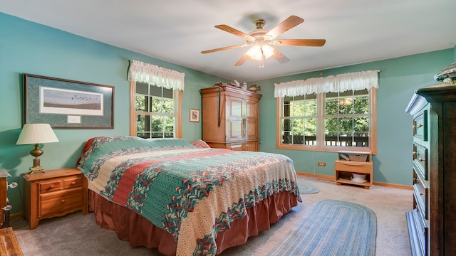 bedroom featuring ceiling fan, light colored carpet, and multiple windows