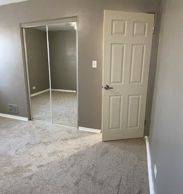 unfurnished bedroom with light colored carpet and a closet