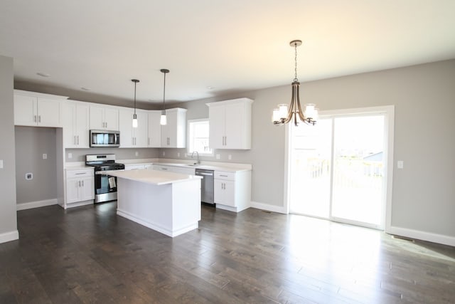 kitchen with pendant lighting, white cabinets, dark hardwood / wood-style flooring, appliances with stainless steel finishes, and a kitchen island