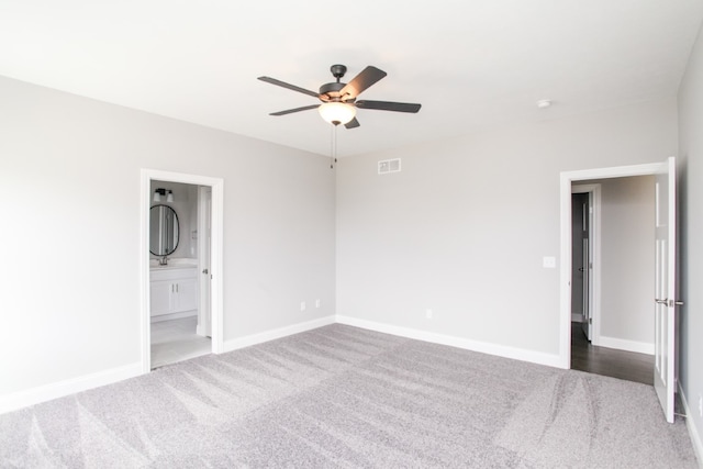 unfurnished bedroom featuring ensuite bath, carpet, and ceiling fan