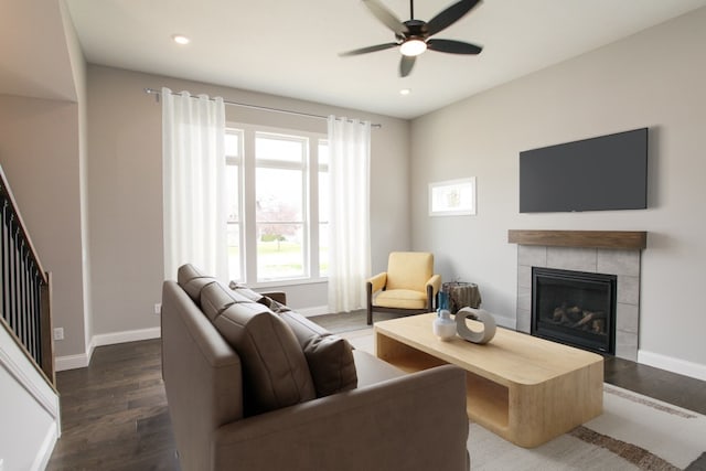 living room featuring ceiling fan, dark wood-type flooring, and a tiled fireplace