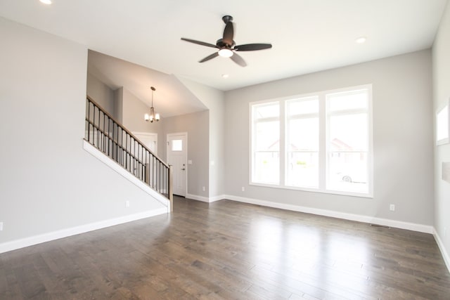 unfurnished living room featuring ceiling fan with notable chandelier and dark wood-type flooring