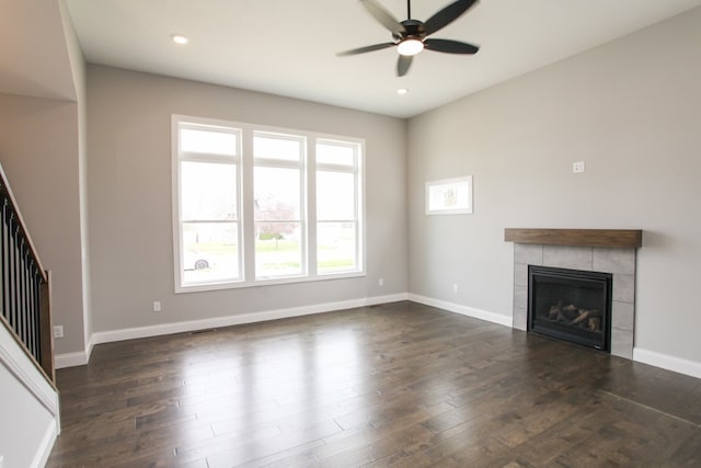 unfurnished living room with ceiling fan, a tile fireplace, and dark hardwood / wood-style floors