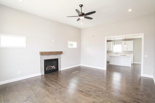 unfurnished living room with ceiling fan, dark hardwood / wood-style floors, a wealth of natural light, and a fireplace