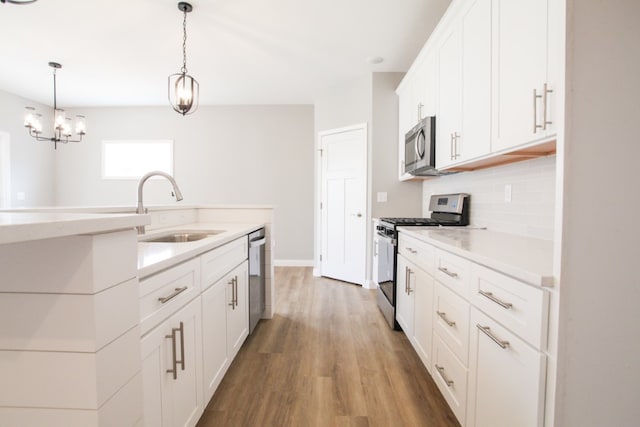 kitchen with white cabinetry, hardwood / wood-style floors, backsplash, appliances with stainless steel finishes, and sink