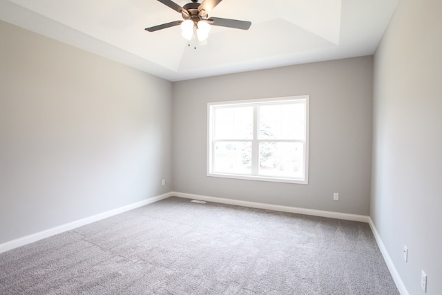 spare room featuring ceiling fan, carpet flooring, and a tray ceiling