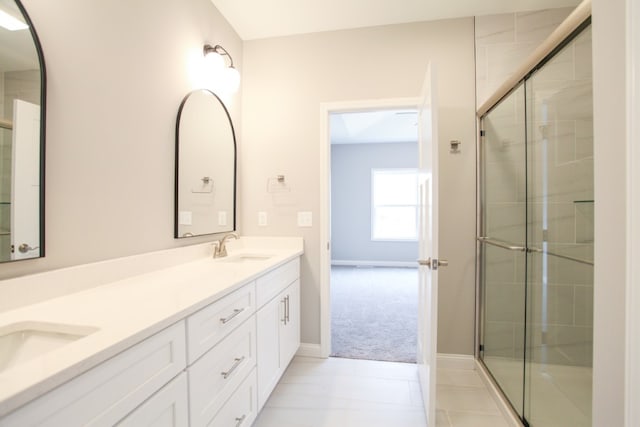 bathroom with a shower with door, large vanity, double sink, and tile flooring