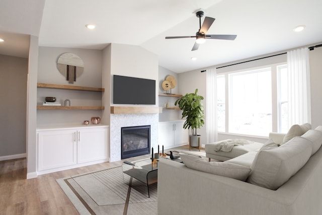 living room with light hardwood / wood-style floors, ceiling fan, and lofted ceiling