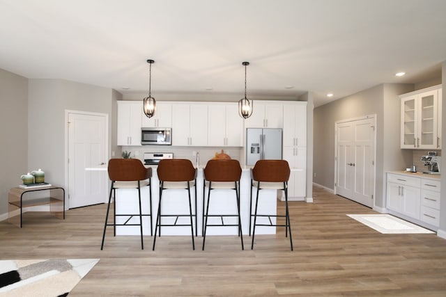 kitchen featuring appliances with stainless steel finishes, light hardwood / wood-style flooring, and white cabinets