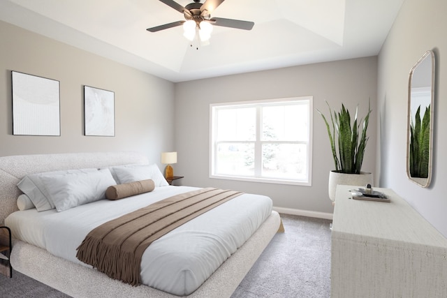 carpeted bedroom featuring ceiling fan and a raised ceiling