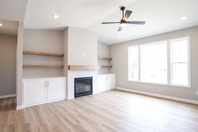 unfurnished living room with light hardwood / wood-style floors, ceiling fan, vaulted ceiling, and a fireplace