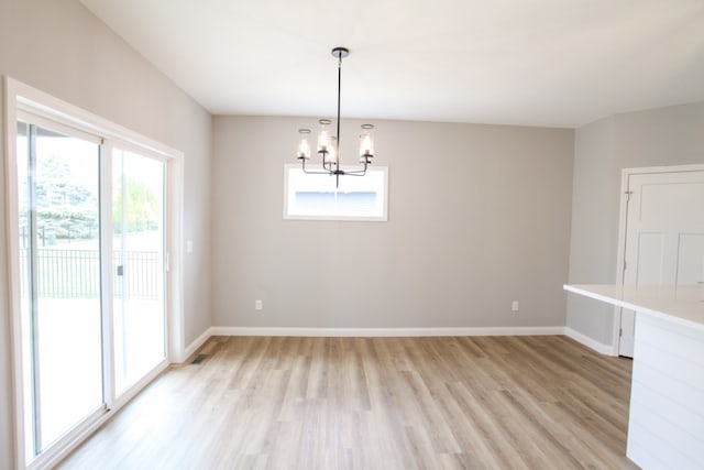 spare room featuring light hardwood / wood-style floors and a chandelier