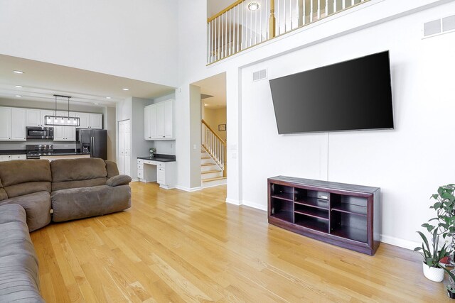 11 N Berkshire Ln, Round Lake, IL 60073 - living area featuring light wood-style floors, stairway, a high ceiling, and a chandelier