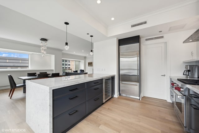 kitchen with high quality appliances, a healthy amount of sunlight, beverage cooler, and light wood-type flooring