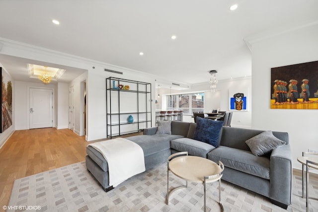 living room with light hardwood / wood-style flooring, an inviting chandelier, and ornamental molding