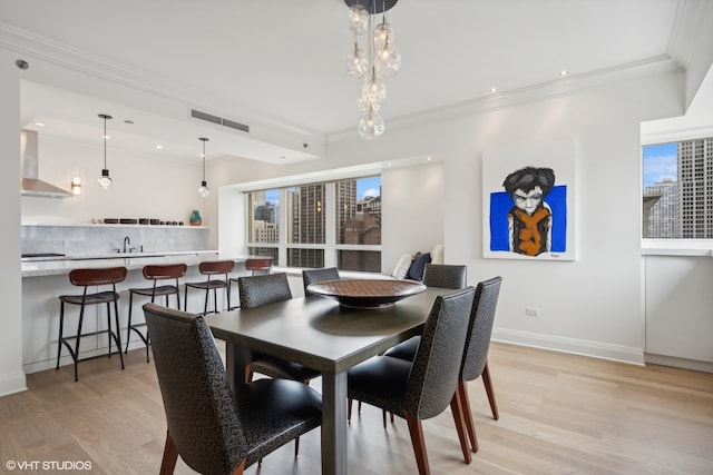 dining area featuring ornamental molding, light hardwood / wood-style floors, and sink