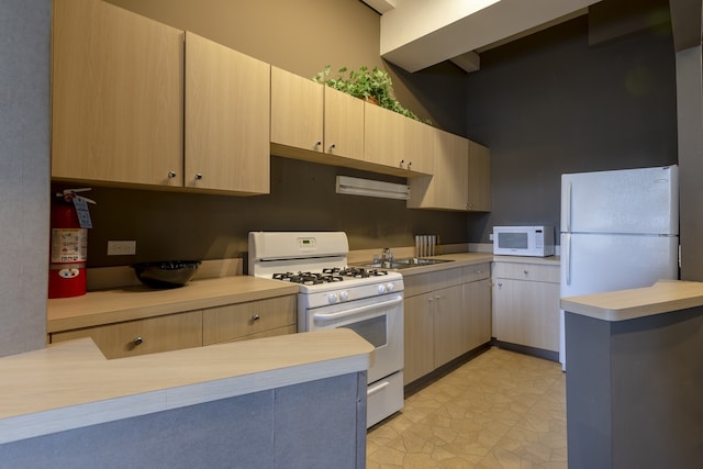 kitchen with sink, white appliances, light tile floors, and light brown cabinets