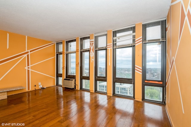 spare room featuring a wall unit AC, a wall of windows, dark hardwood / wood-style flooring, and a textured ceiling