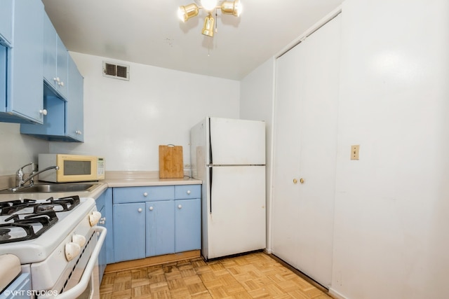 kitchen with light parquet floors, white appliances, sink, and blue cabinetry