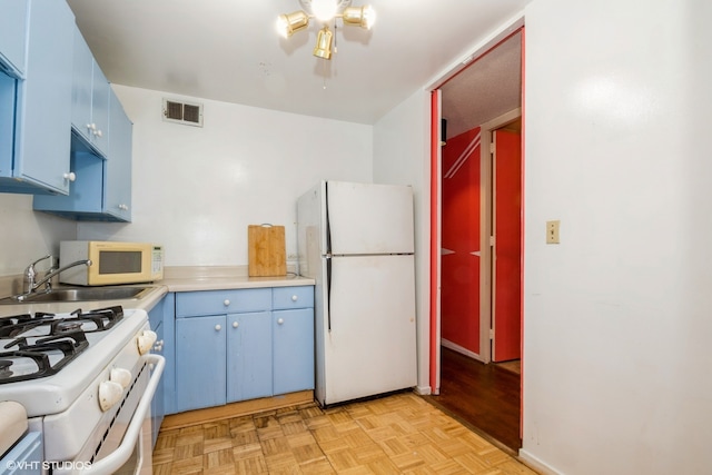 kitchen with sink, white appliances, blue cabinets, and light wood-type flooring