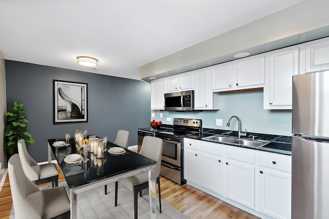 kitchen featuring stainless steel appliances, white cabinetry, sink, and light wood-type flooring